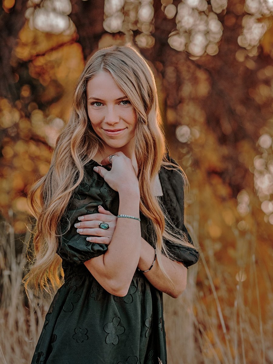 A high school senior standing among warm autumn leaves in the Tri-Cities