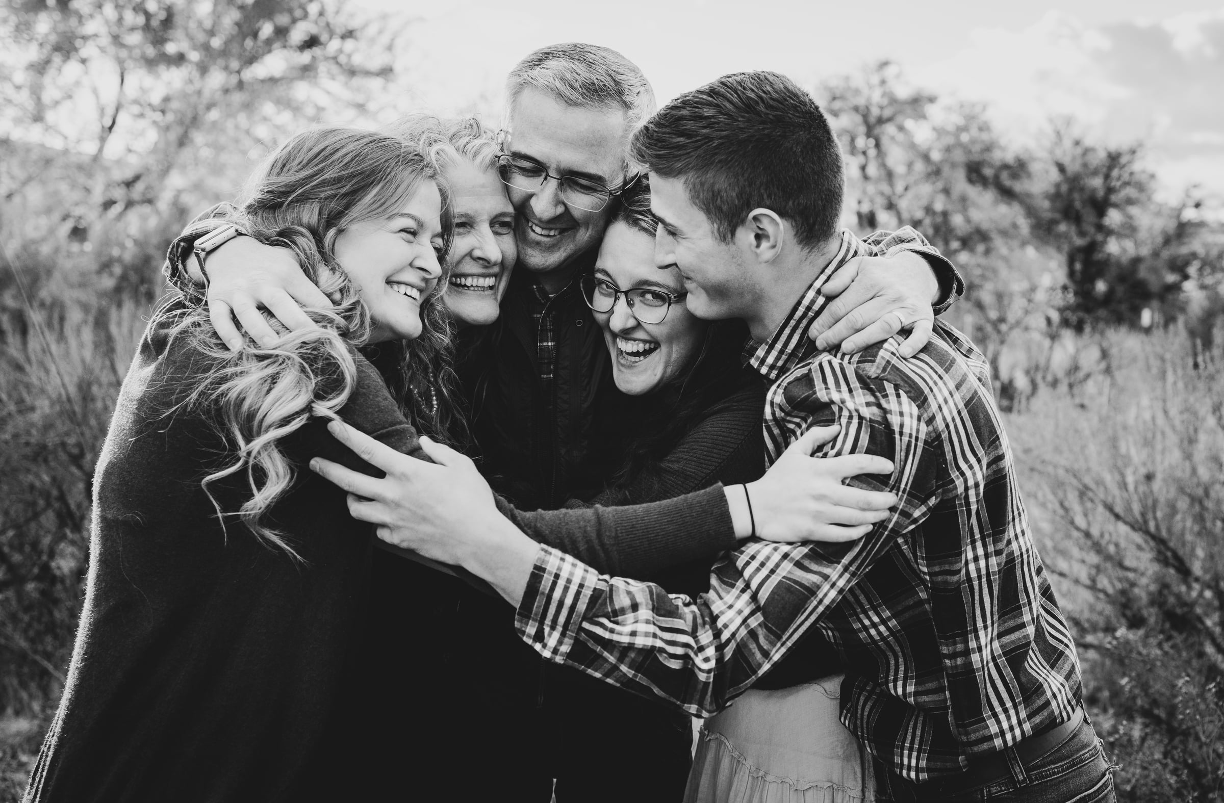 An extended family laughing together in a close black-and-white portrait