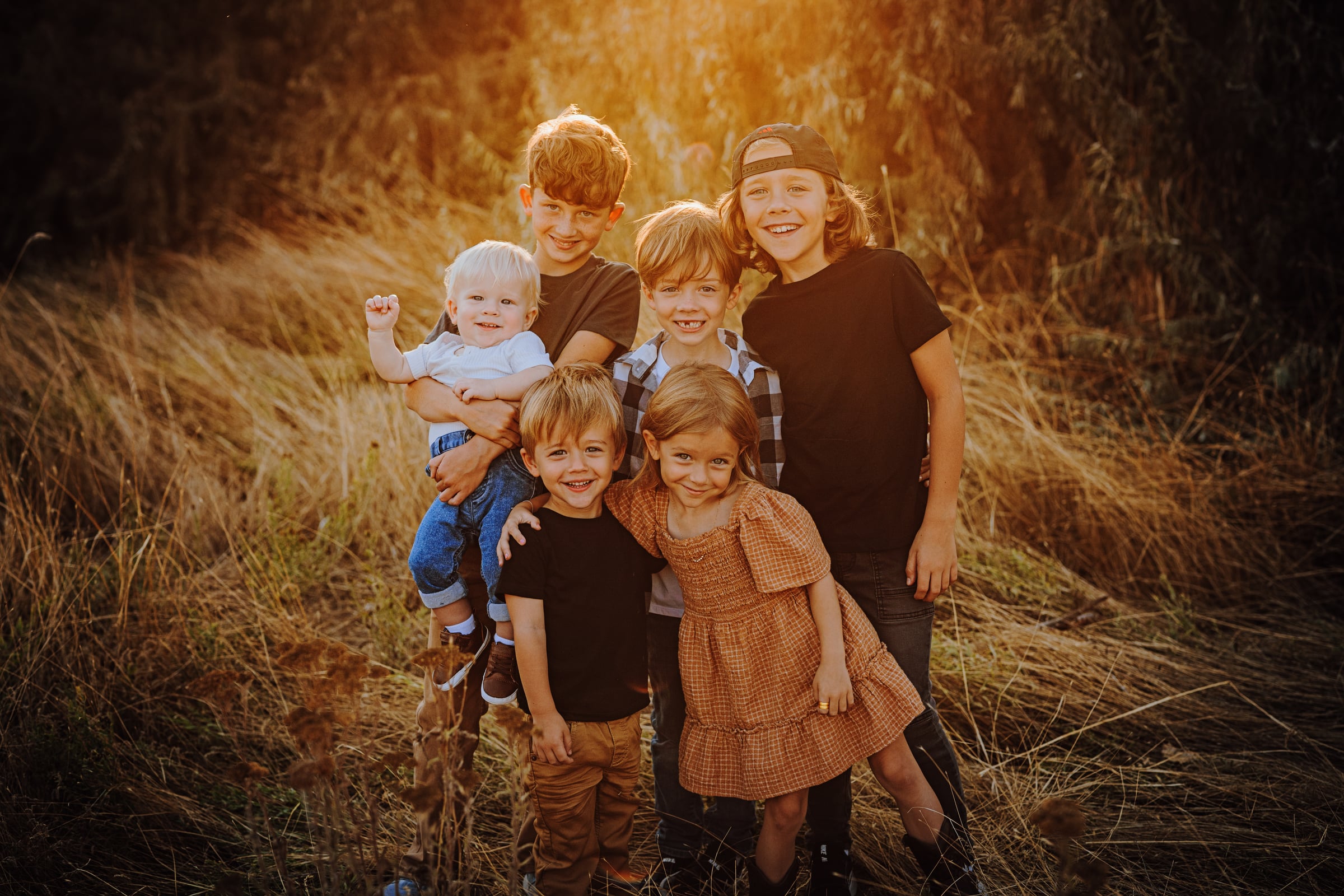 Six children smiling together in warm evening light during a Tri-Cities family session
