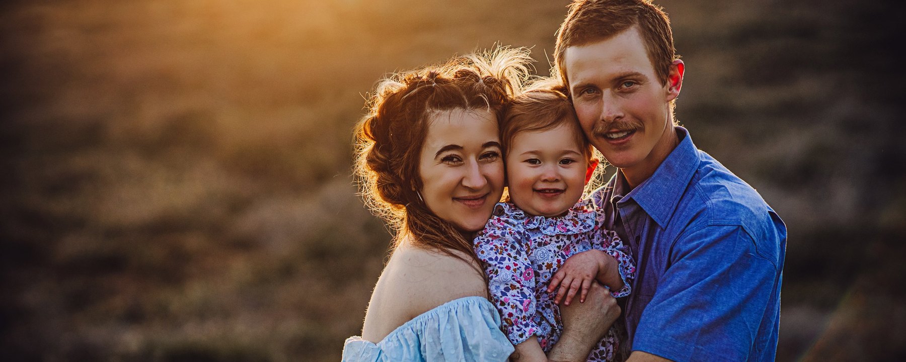 Parents holding their young child in glowing Columbia Basin evening light