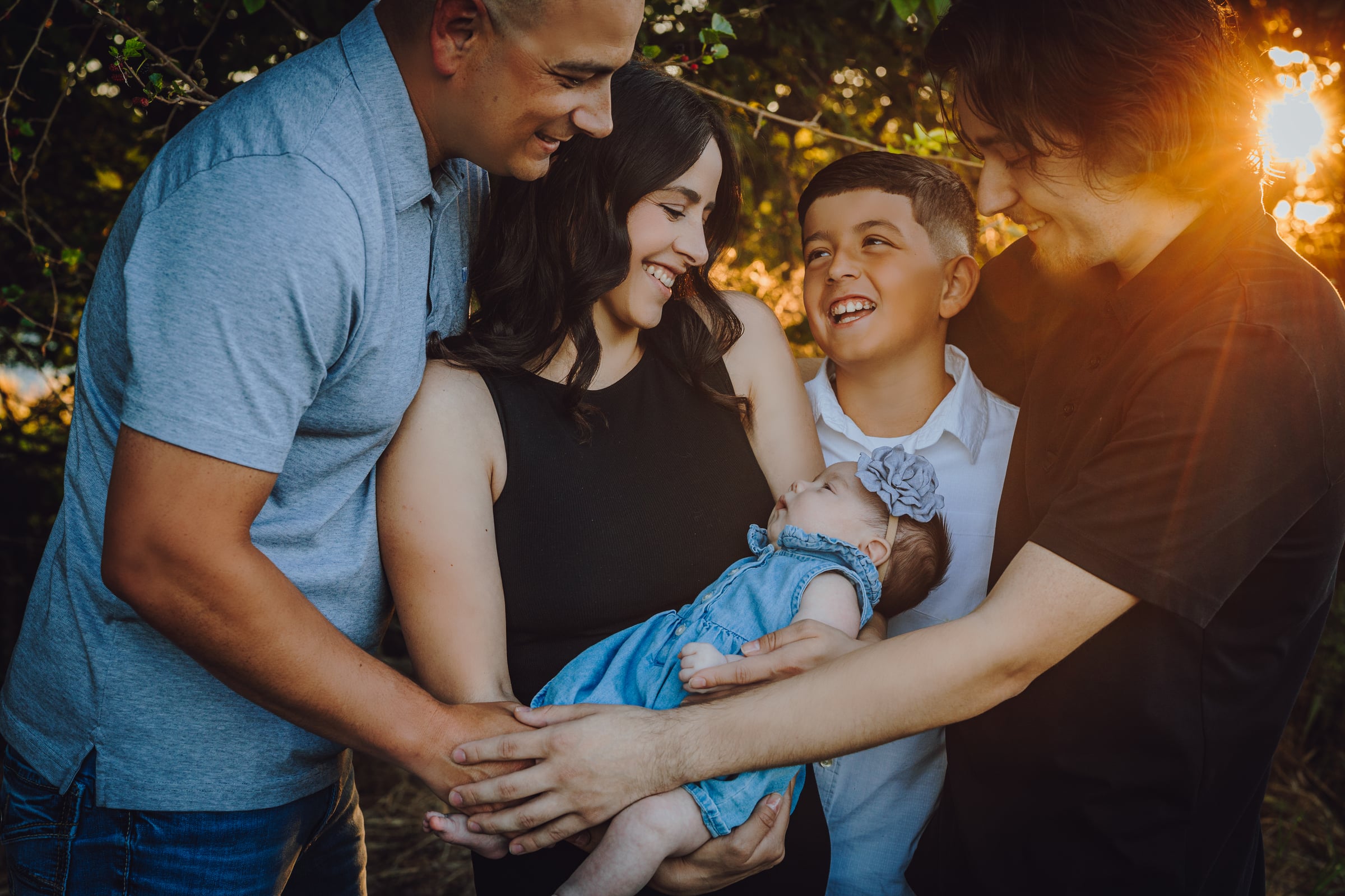 Family gathered around their baby in warm sunset light in the Tri-Cities