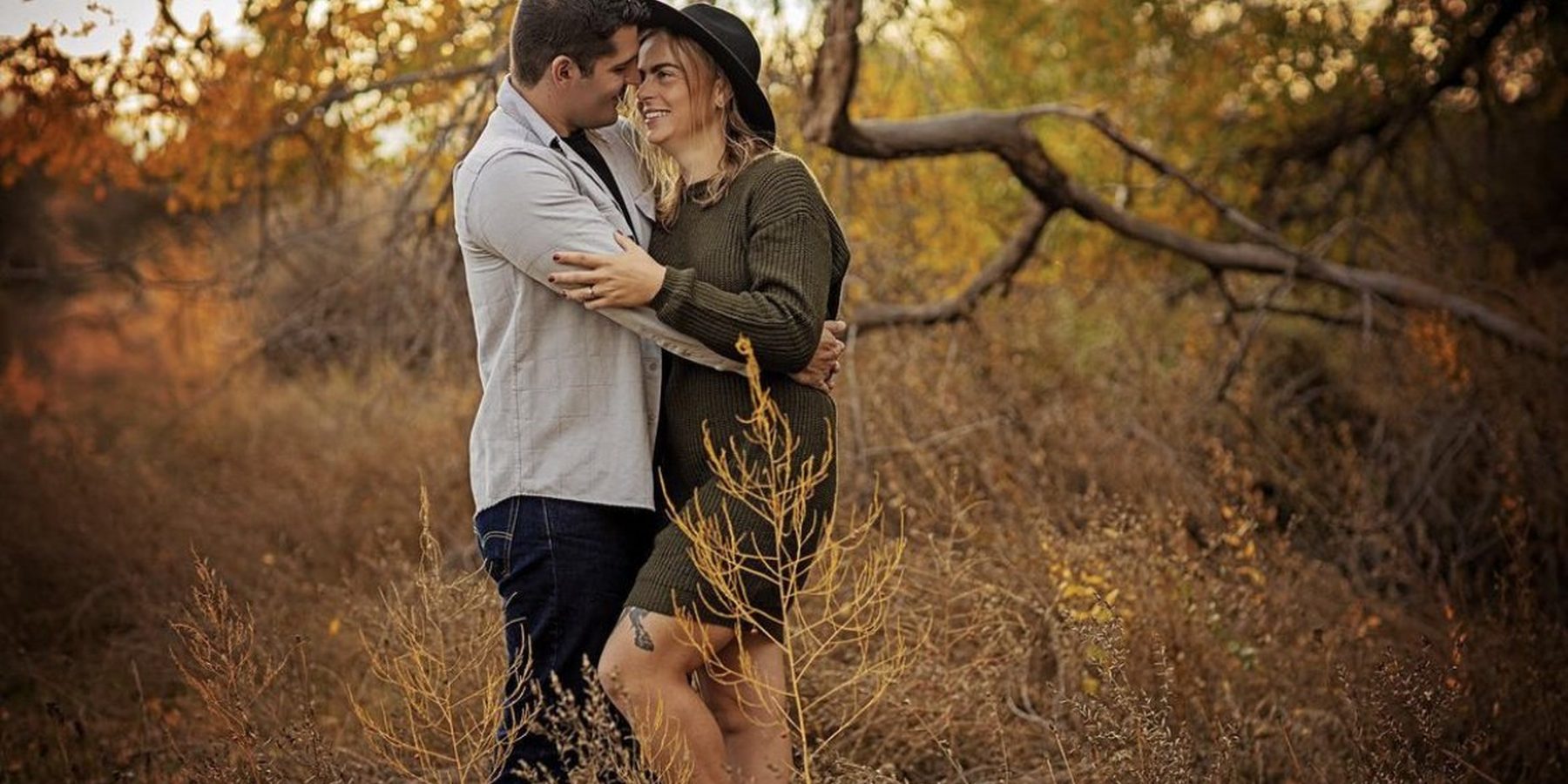 A couple sharing a quiet embrace beneath autumn trees during a golden-hour session in Richland, WA