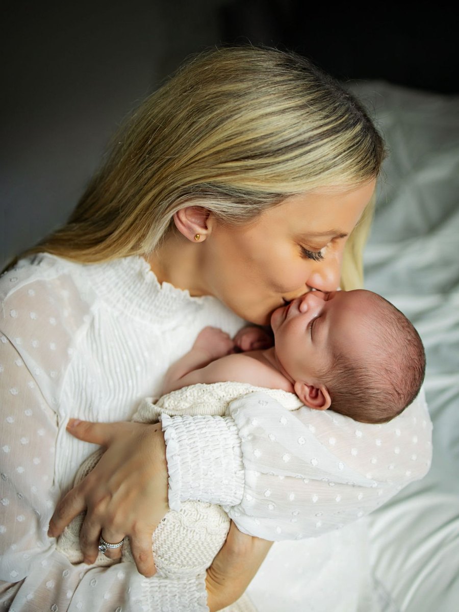 A mother kissing her newborn during a gentle in-home newborn session in Richland