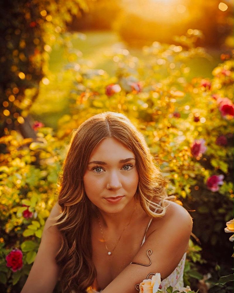 A senior seated among flowers in warm golden evening light